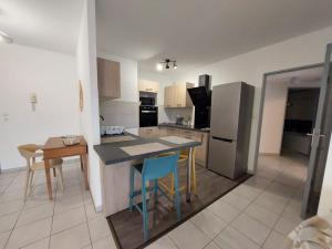 サン・ピエールにあるAppartement cosy au bord de merのテーブルと椅子と冷蔵庫のあるキッチン