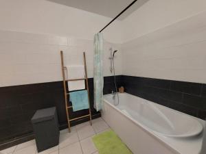 サン・ピエールにあるAppartement cosy au bord de merのバスルーム(白いバスタブ、緑のラグ付)