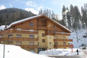 a large building in the snow with a person in front at Haus Rätia App 17 in Klosters