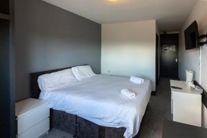 een slaapkamer met een bed met witte lakens en kussens bij Pelham Hotel in Immingham