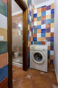 y baño con azulejos de colores, lavadora y secadora. en Apartamento LLanos de belen, en Ardales