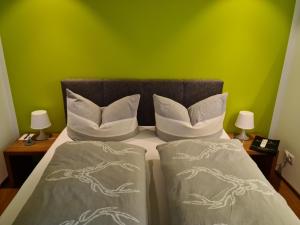 um quarto com uma cama com duas almofadas e uma parede verde em Ammann Marika em Vandans