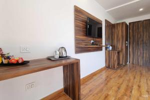 Moon Glade By Stylia Hotels في دالهوزي: غرفة مع منضدة خشبية مع تلفزيون على الحائط