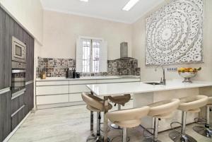 a kitchen with a white counter and stools in it at Palacete del Porvenir in Seville