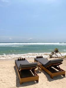 アハンガマにあるHarding Boutique Hotelの海のそばのビーチにある長椅子2脚