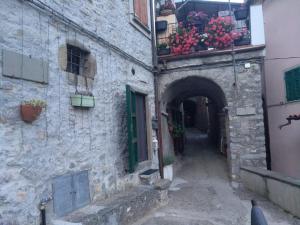 an alley in an old stone building with flowers in a window at La pietra di Sersa in Quaratica