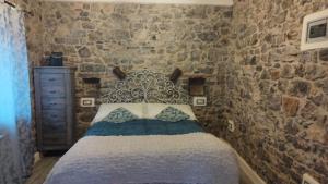 a bedroom with a bed with a stone wall at La pietra di Sersa in Quaratica
