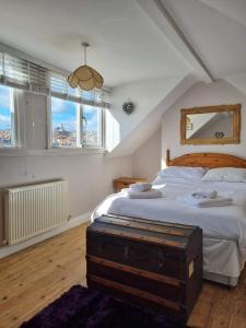 a bedroom with a large white bed and windows at Endeavour Cottage - A Wonderful Whitby Holiday in Whitby