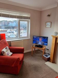 a living room with a red couch and a tv at Endeavour Cottage - A Wonderful Whitby Holiday in Whitby