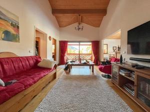a living room with a red couch and a tv at Chalet l'Arnica in Les Gets