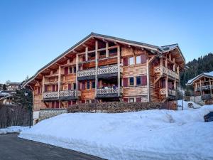 a large wooden house with snow in front of it at Chalet l'Arnica in Les Gets