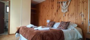 a bedroom with a large bed with wooden walls at Hostal Los Pinos in Puerto Natales