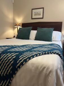 - un grand lit avec une couverture bleue et blanche dans l'établissement John Barleycorn, à Duxford