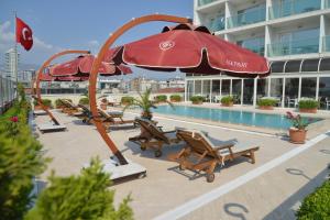 a pool with chairs and umbrellas next to a building at Ege Palas in İzmir