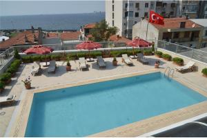 a swimming pool on top of a building with chairs and umbrellas at Ege Palas in İzmir