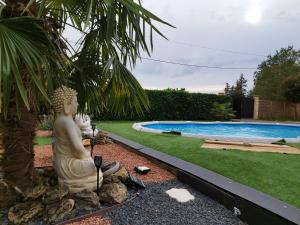 une statue d'un buddha assis à côté d'une piscine dans l'établissement La Cordonnerie de Las Places, à Campagne-dʼArmagnac