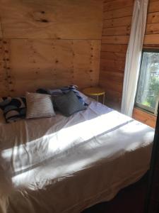 a bed in a log cabin with a window at Cabaña Rustica en lagunillas con vista al mar in Navidad