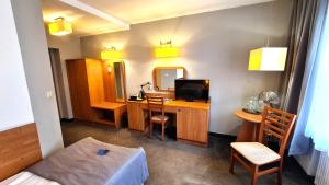 a room with a desk with a television and a bed at Hotel Malinowski Economy in Gliwice