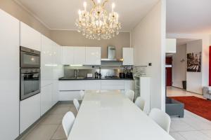 una cocina blanca con una mesa blanca y una lámpara de araña en Easylife - Spacious apartment in Maciachini, en Milán