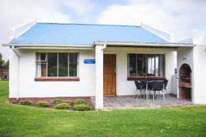 Casa blanca con mesa y sillas en Tsitsikamma Cottages en Witelsbos