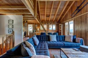 een woonkamer met een blauwe bank en houten plafonds bij Chalet Bellevue in La Tzoumaz