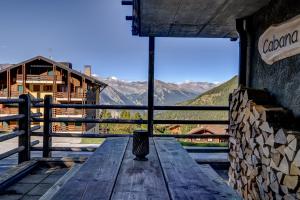 a wooden table on a balcony with a view of mountains at Chalet Cabana Luna in La Tzoumaz