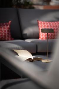 a lamp and an open book on a table next to a couch at Caracciolo 13 Rooftop & Suites in Naples