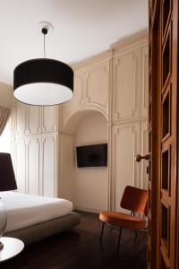een slaapkamer met een bed, een stoel en een lamp bij Caracciolo 13 Rooftop & Suites in Napels