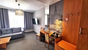 a hotel room with a desk and a living room at Hotel Malinowski Economy in Gliwice