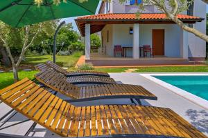 dwa drewniane krzesła i parasol obok basenu w obiekcie Villa Agatha w mieście Krnica