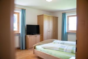 a bedroom with a bed and a flat screen tv at Fortschöllhof in Castelrotto