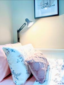 a lamp sitting on top of a bed with pillows at FARIDZ Homestay at Myra Saujana in Kampong Simpang Empat