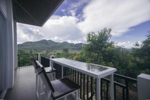 a balcony with a table and a chair and mountains at Hakata Lejja near Natural Hot spring in Batu-Batu