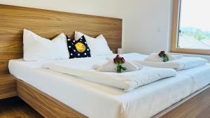 a large white bed with white pillows and flowers on it at Apartment SCHLADMING - Planai view in Schladming