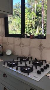 a stove top in a kitchen with a window at casa natureza Mariscal in Bombinhas +8 photos