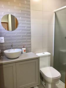 a bathroom with a sink and a toilet and a mirror at casa natureza Mariscal in Bombinhas +8 photos