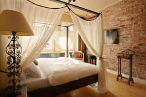 ワルシャワにあるスリープウェル アパートメンツ オルディナチカのレンガの壁、天蓋付きベッドが備わるベッドルーム1室が備わります。
