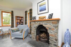 sala de estar con chimenea de piedra y silla en Kennacraig Lodge en Whitehouse
