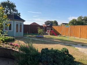 um quintal com um parque infantil e um baloiço em Delightful self-contained Annexe close to airport em Norwich