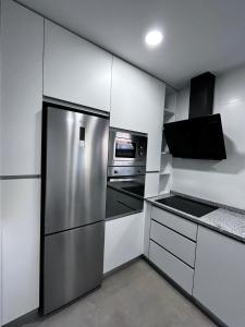 uma cozinha com um frigorífico de aço inoxidável e um micro-ondas em Barros' House em Chaves