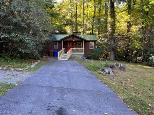 a small house in the woods with a driveway at Cozy Cabin Pet Friendly ADA Compatible in Maggie Valley