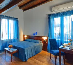 1 dormitorio con 1 cama azul, mesa y sillas en Hotel La Plumeria en Cefalú