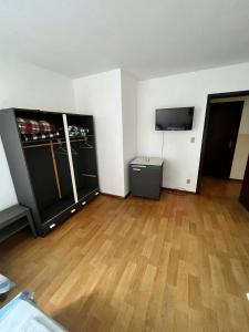 a room with a hard wood floor and a tv at Hotel São José in Ponta Grossa