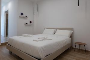 Un dormitorio blanco con una cama con dos zapatillas. en All'Uscita B&b, en Éboli