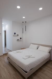 All'Uscita B&b في إبولي: غرفة نوم بيضاء مع سرير كبير بجدران بيضاء