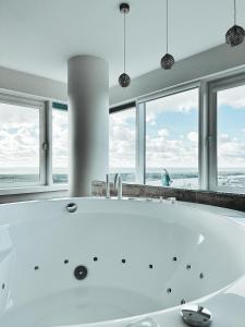 a white bath tub in a room with windows at sky DREAM jacuzzi sauna 33 FLOOR in Klaipėda