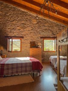 - une chambre avec 2 lits et un mur en pierre dans l'établissement L´estudi, à El Meüll