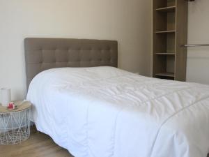 a bedroom with a white bed with a brown headboard at Maison de vacance in Cabourg