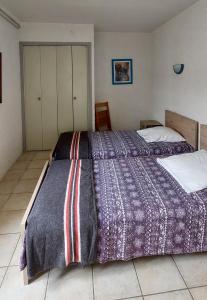 a bedroom with a large bed with a purple comforter at La Ginelle - Appartement Isba in Airoux