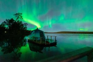 a boat in the water under the northern lights at Aurora Nest – Eco Glass Igloo in Rovaniemi